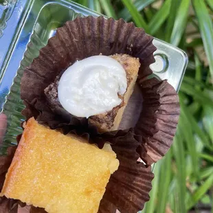 a hand holding a piece of cake with whipped cream