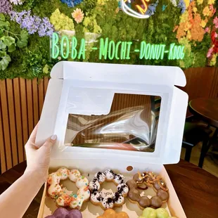 a person holding a box of doughnuts