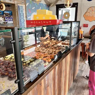 a woman standing in front of a display of pastries