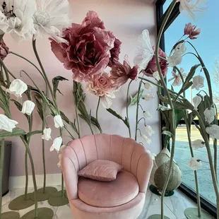 a pink chair and a vase of flowers