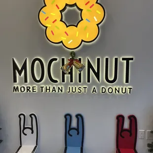 three chairs in front of a sign that says mochinut more than just donut