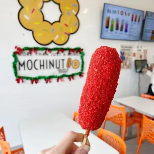 a hand holding a red doughnut