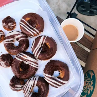 a tray of chocolate donuts and a cup of coffee