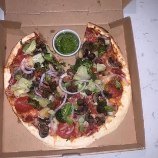 a pizza in a box with a face made out of vegetables