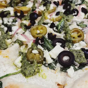 a pizza with olives, spinach, and feta cheese