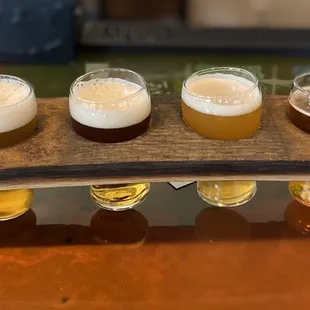 four glasses of beer on a wooden tray