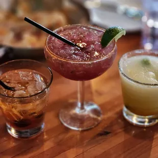 three different cocktails on a wooden table