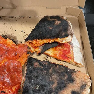 a burnt pizza in a box