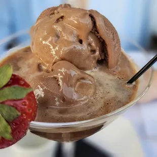 Chocolate desert with some sort of alcohol served with a spoon and straw
