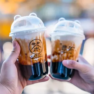 two people holding cups of iced coffee