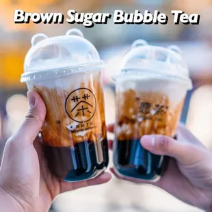 two people holding cups of brown sugar bubble tea