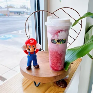 a cup of milkshake with a mario figure next to it