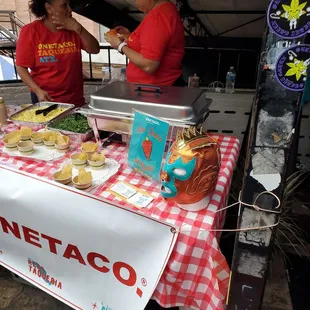 two women in red shirts preparing food on a table