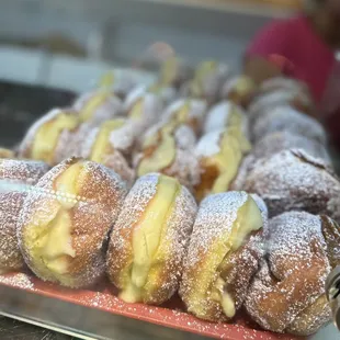 a tray of doughnuts covered in powdered sugar