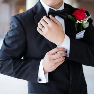 Groom getting ready showing cuff link red rose boutonniere