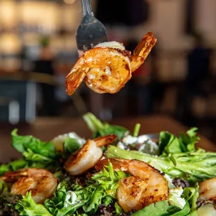 a plate of salad with shrimp and lettuce