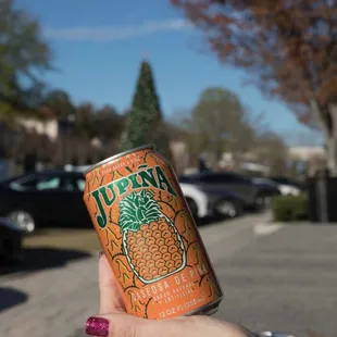 a person holding a can of juice