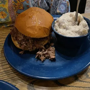 ows a pulled pork sandwich with a side of mashed potatoes