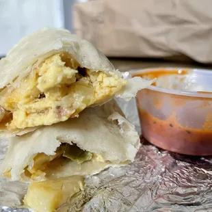 a breakfast burrito and a bowl of sauce