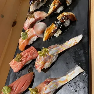 a variety of sushi on a black plate