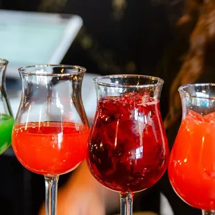 a row of three glasses filled with drinks