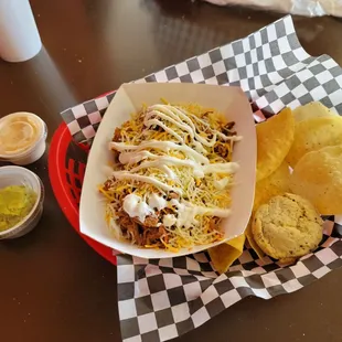 Brisket bowl with rice, pinto beans, cheese, and sour cream. This is next to some guacamole, chipotle ranch, chips and a cookie.