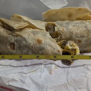 Breakfast burrito made of carne asada, eggs, cheese, and flour tortilla.