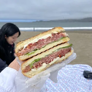 a woman holding a sandwich on the beach