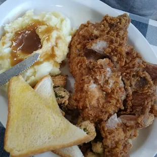 Fried pork chops, mashed potatoes and gravy and fried okra.