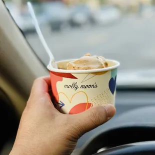 a hand holding a cup of ice cream