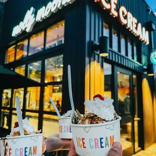 two people holding up ice cream bowls