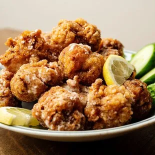 a plate of fried chicken with a side of cucumbers
