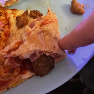 a hand reaching for a slice of pizza