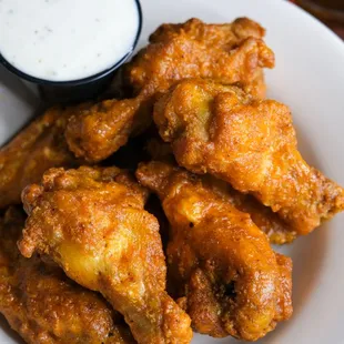 a plate of fried chicken wings with a side of ranch dip