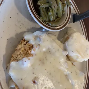 Chicken fried chicken with mashed potatoes and green beans and whole lot of gravy