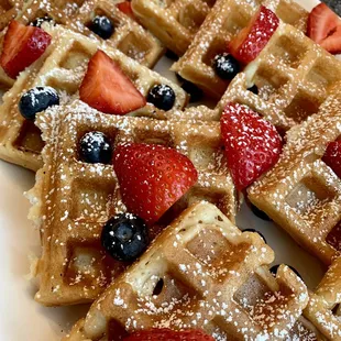 a plate of waffles with strawberries and blueberries