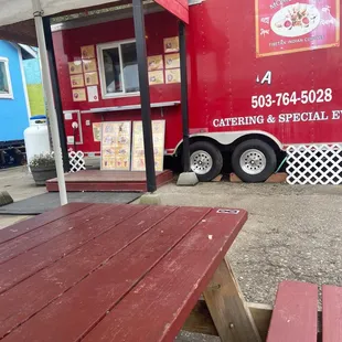 a red food truck and picnic table