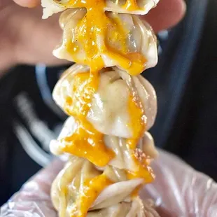 Delicious pork momos drizzled with our spicy secret sauce!