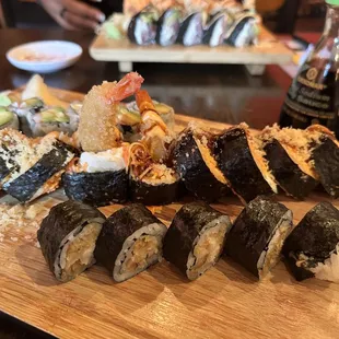 a wooden cutting board with a variety of sushi on it