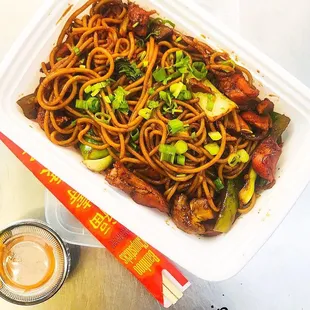 a container of noodles with meat and vegetables