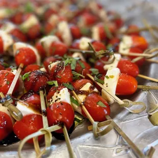 a platter of cherry tomatoes and mozzarella skewers