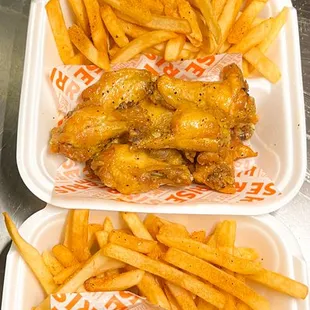 three trays of chicken wings and french fries