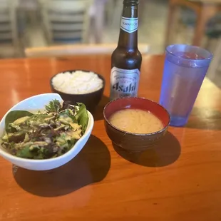 a bowl of salad and a bottle of beer