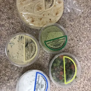 Pita bread, cilantro jalapeño hummus, garlic chive hummus, cucumber salad, and Tzatziki