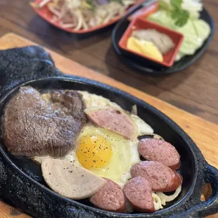 a steak, eggs, and sausage in a cast iron skillet