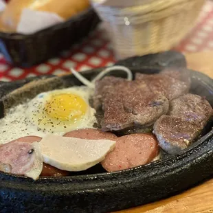 sausages, eggs, and sausages cooking in a cast iron skillet