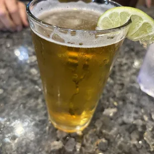 a glass of beer with a lime wedge