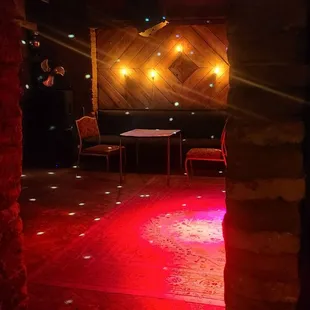 a stage with red lighting and a table and chairs