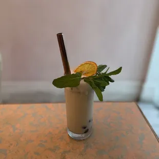 a drink in a glass with a garnish of orange and mint