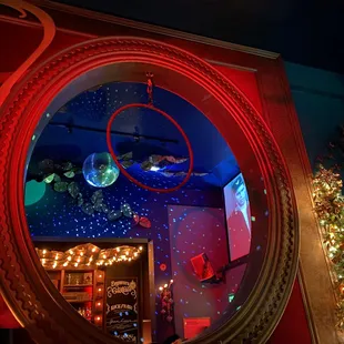 a bar with a circular mirror and a christmas tree in the background